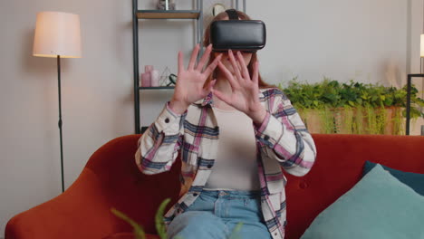 young woman use virtual reality headset glasses at home, enjoying video concept moving hands in air