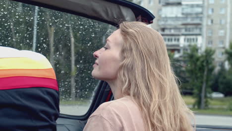 woman in a vintage convertible on a rainy day