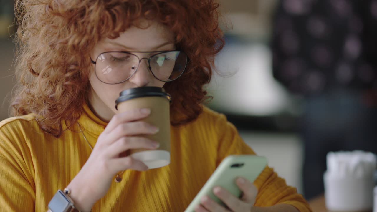 retrato hermosa joven pelirroja usando teléfono inteligente en un café navegando en línea mensajes de redes sociales disfrutando de beber café compartiendo estilo de vida leyendo teléfono móvil comunicación usando gafas