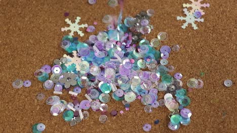 cold colored sequins falling on a cork mat