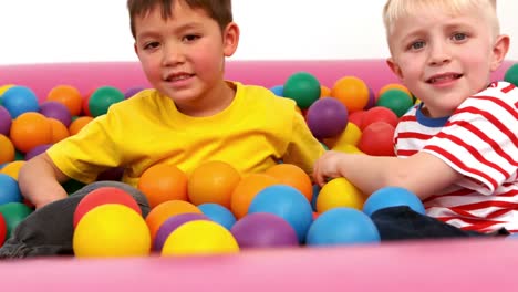 two boys playing in a ball pit