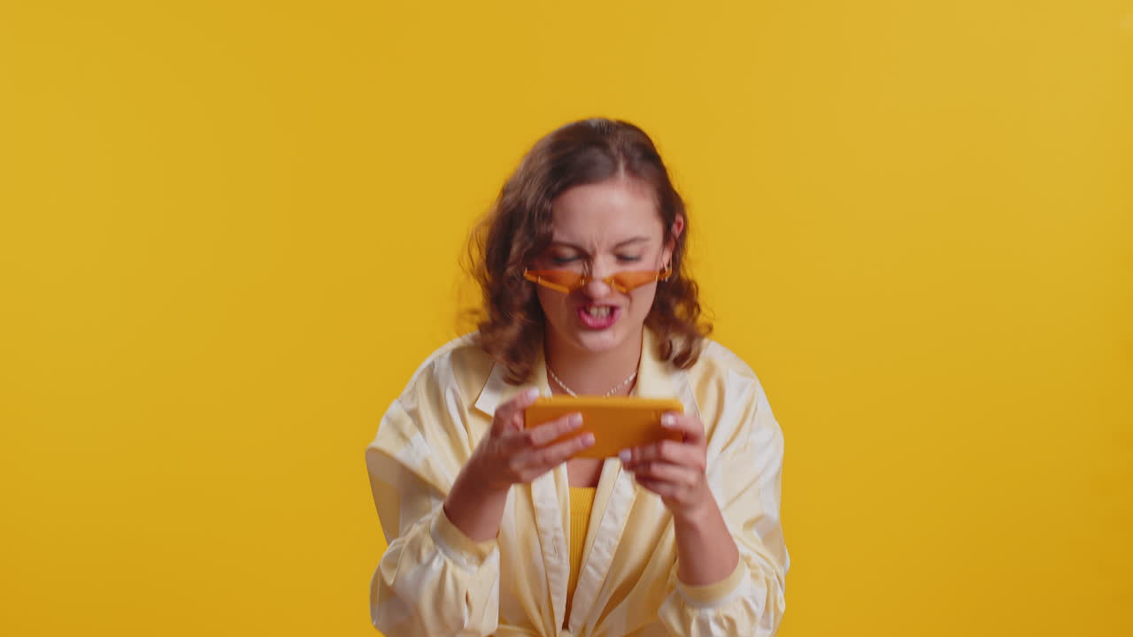 걱정스럽고 재미있고 중독된 관광객 소녀가 휴대폰에서 드라이브 레이싱 비디오 게임을 열정적으로 즐기고 있습니다.