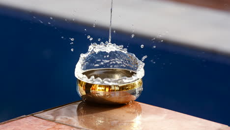 slow motion video of an object dropping into the water of a bowl and water splashes out