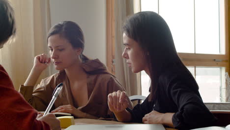 camera focuses on two girls of a study group who are listening to their classmate's explanation