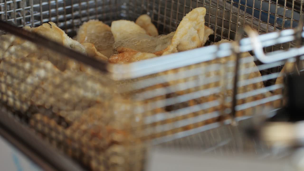 Cooking Chinese and Japanese Jiaozi or gyoza in boiling oil close-up. Dumplings with meat pouring red sweet chilli sauce. Cooking at cafe, restaurant. Asian street food market outdoors