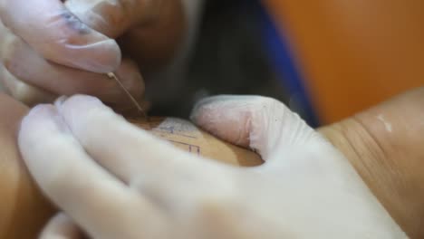 cerrar la mano de una mujer enguantada hace un tatuaje de palo y pinchazo en el tobillo de una clienta
