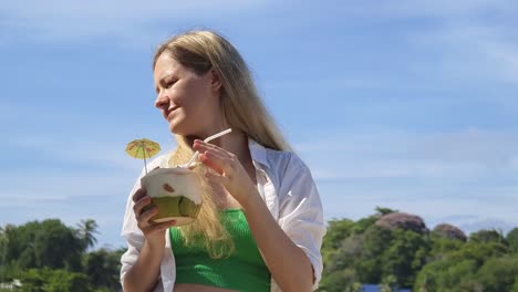 mujer disfrutando de una bebida de coco en un día soleado