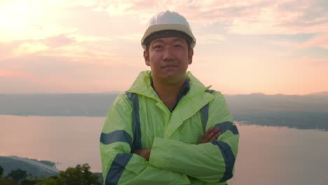 a man engineer is putting a protective helmet on her head at sunset.