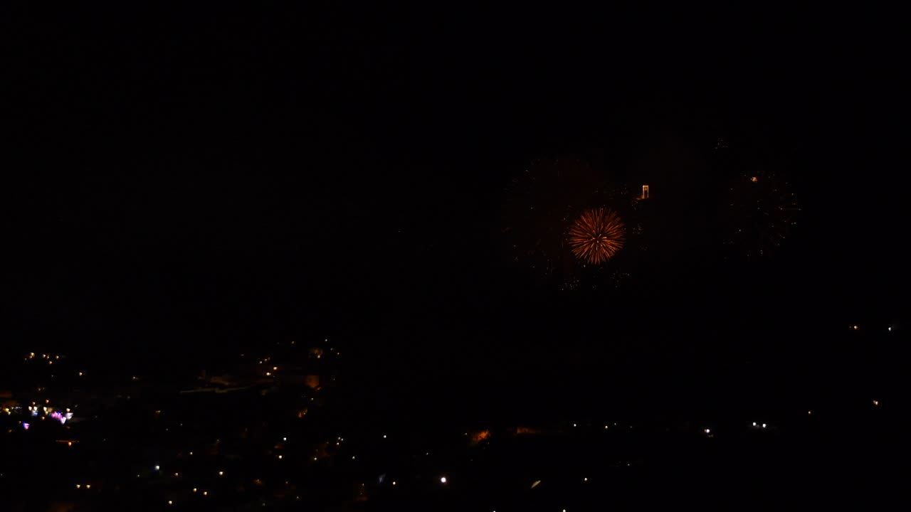 밤에 산 마을에서 많은 금빛과 반짝이는 불꽃놀이로 축하