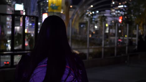 東京、渋谷のミヤシタパークショッピングモールの屋上を夜に歩く若いアジア人女性観光客の背面ショット