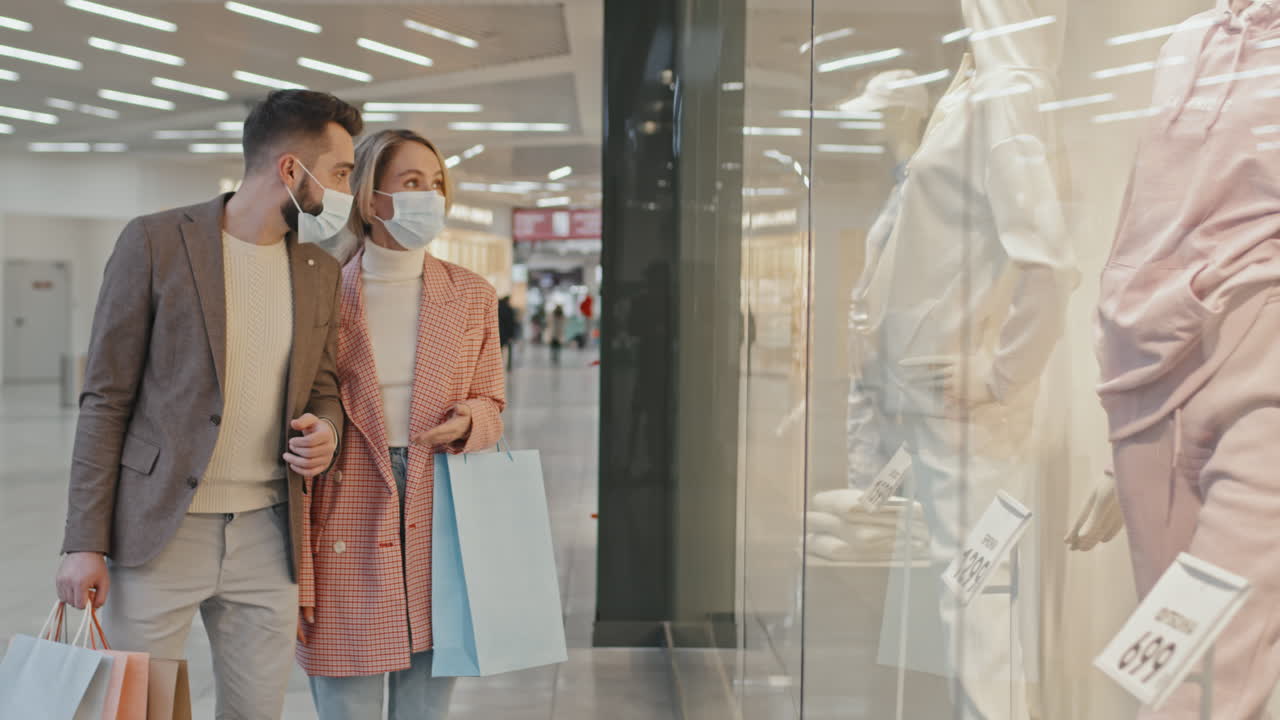 Modern Couple In Face Masks Shopping For Clothes