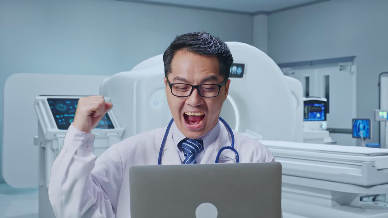 Close Up Of Asian Male Doctor Looking At A Laptop And Celebrating The Succeed With MRI Machine In The Hospital