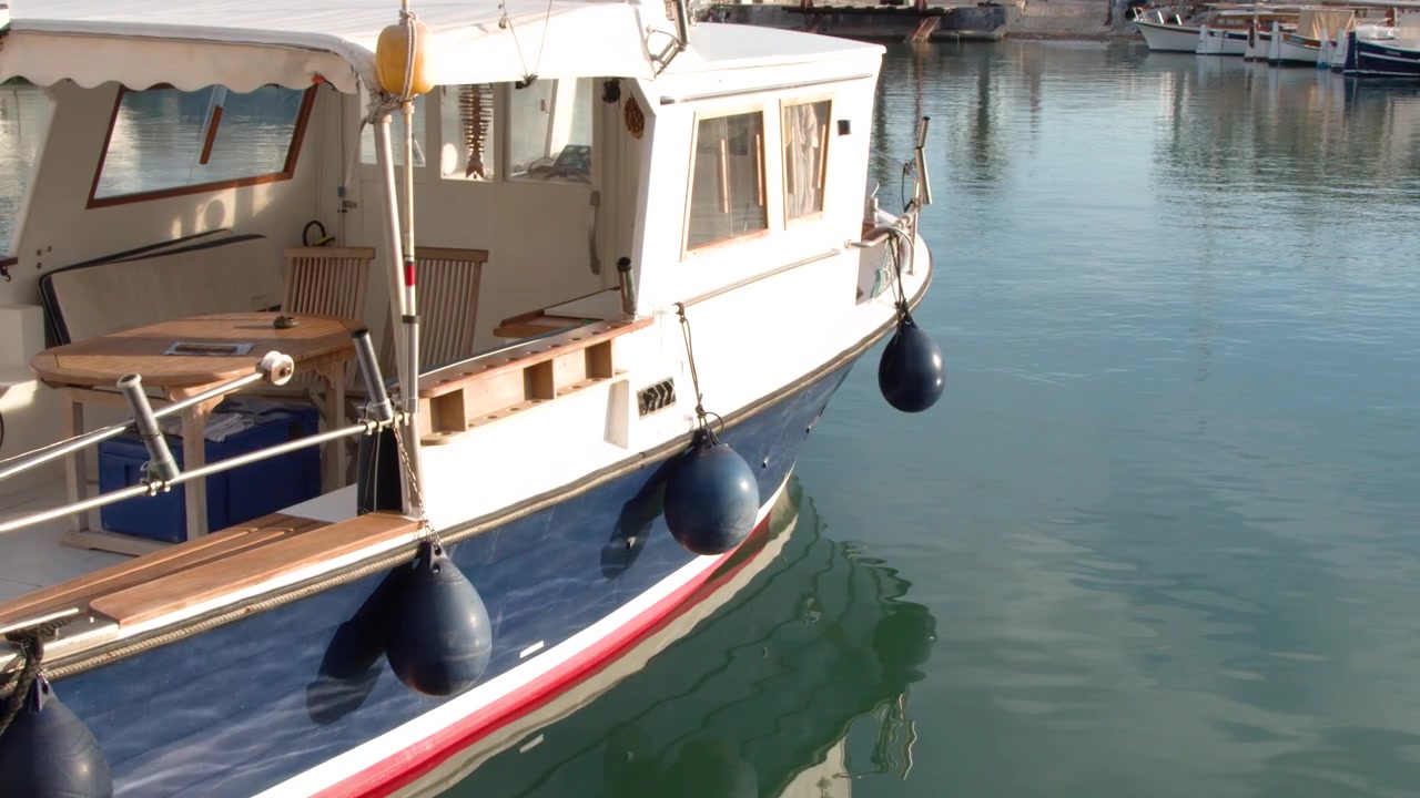 Inquadratura media statica di una barca di legno blu e bianca ormeggiata in acque calme del porto