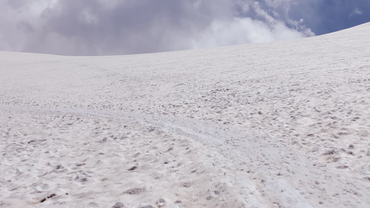 Aerial drone shot revealing clouds over snow-covered Swiss Alps in Zermatt on a sunny day