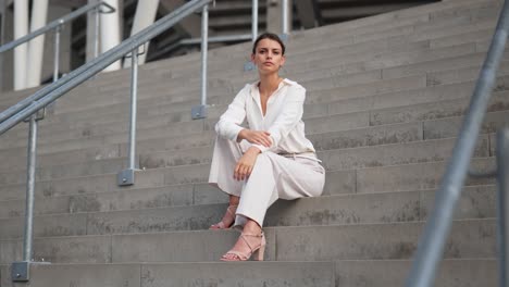 A-young-beautiful-model-sits-on-steps-and-looks-at-the-camera