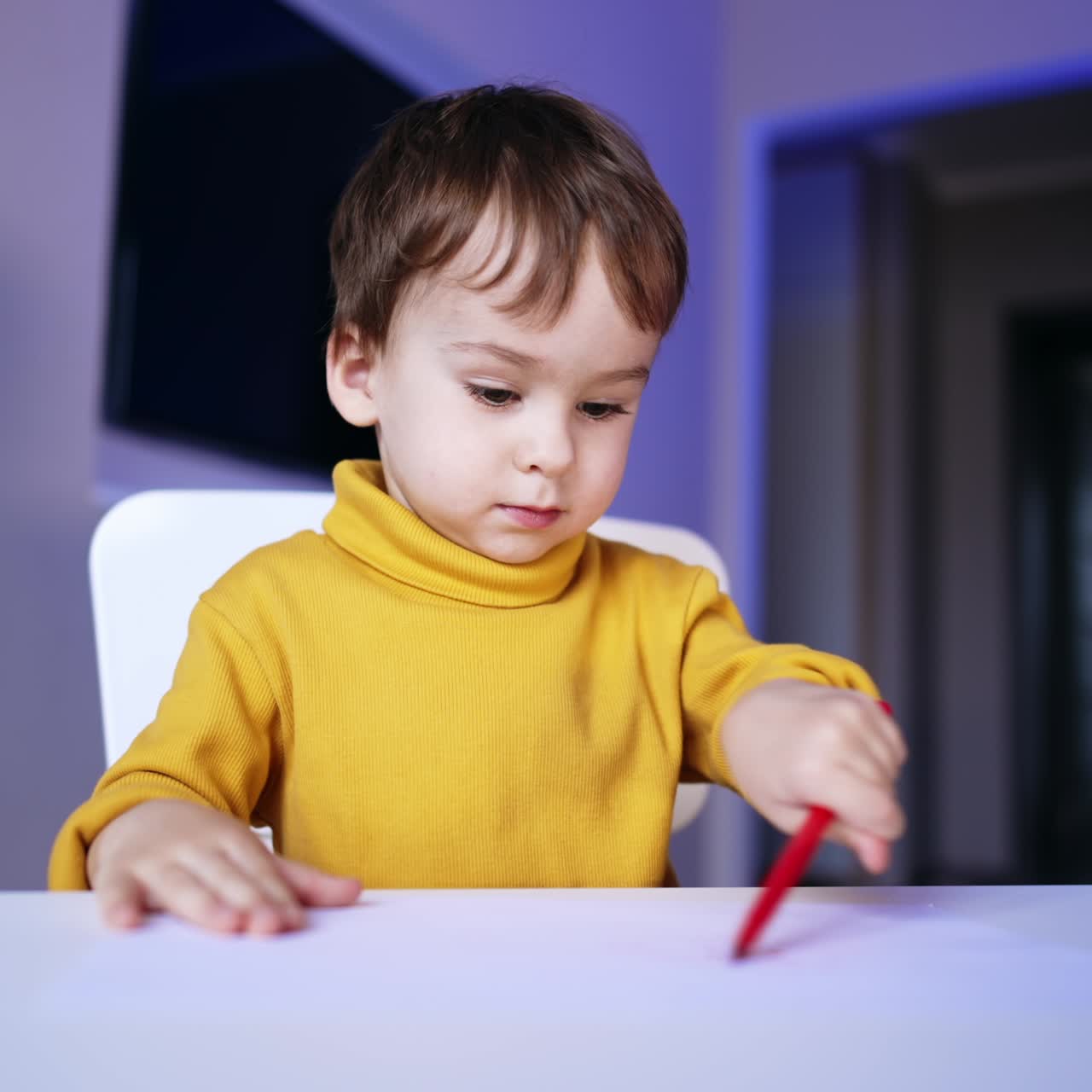 Bambino concentrato che disegna su carta con una penna rossa. Adorabile bambino che impara a usare un pennarello a casa.