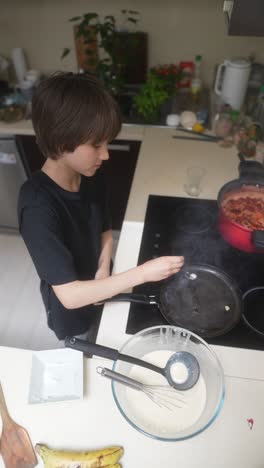 young boy cooking pancakes