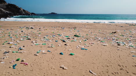 Polluted-Waste-on-a-Beautiful-Beach-with-Crashing-Waves-in-the-Background-in-Binh-Hung,-Vietnam