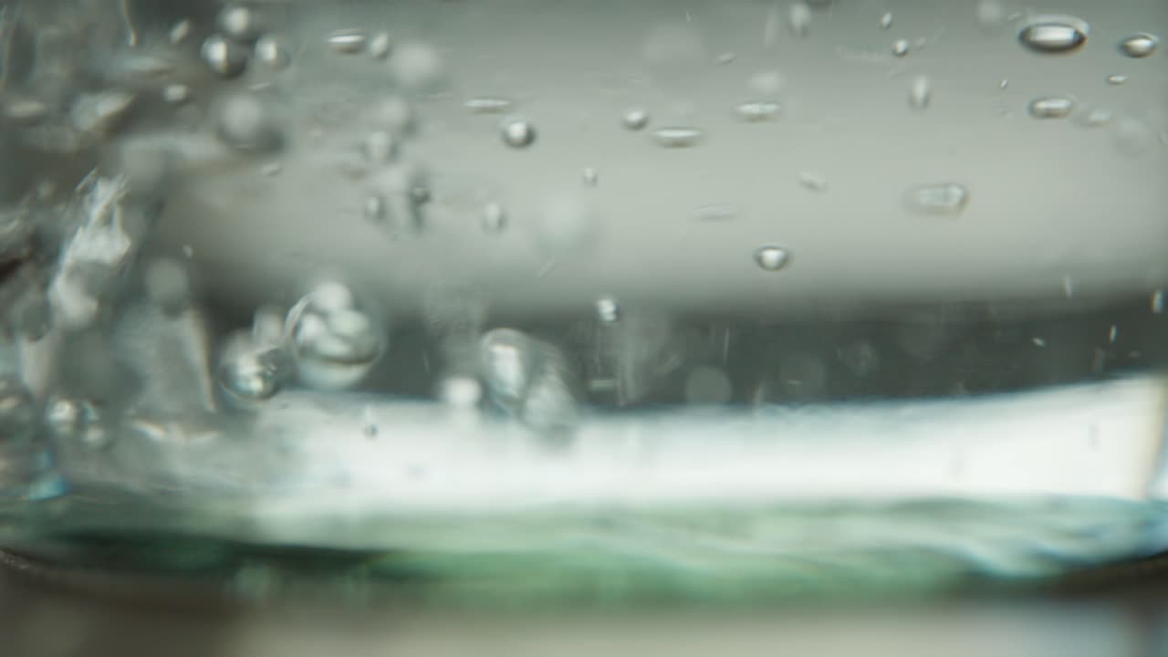 Slowmo of water being poured into the bottom of a glass