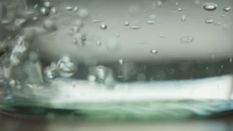 slowmo of water being poured into the bottom of a glass