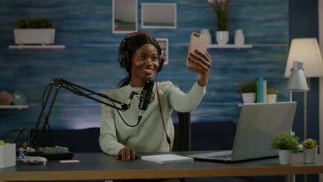 african woman using smartphone taking selfie during podcast