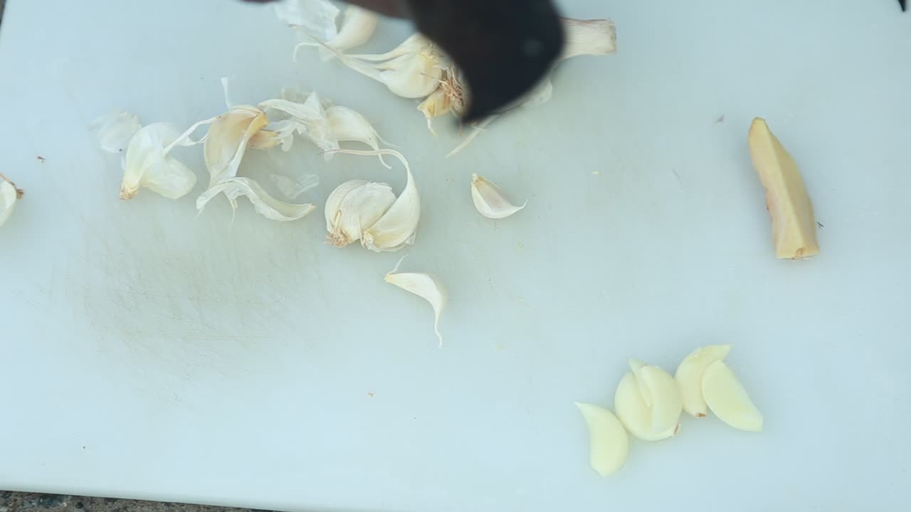 Peeling garlic on the chopping board ,traditional outdoor cooking , It is taken from the board, broken up with a knife and stacked to one side