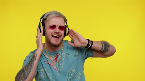 cheerful attractive man listening music via headphones and dancing disco fooling around having fun