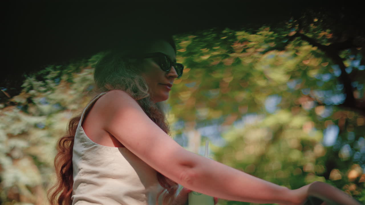 Close up of woman holding an iced matcha latte outdoors while pushing a stroller