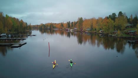 tourists enjoying scenic fall colors lining calm river on kayaking tour, finland