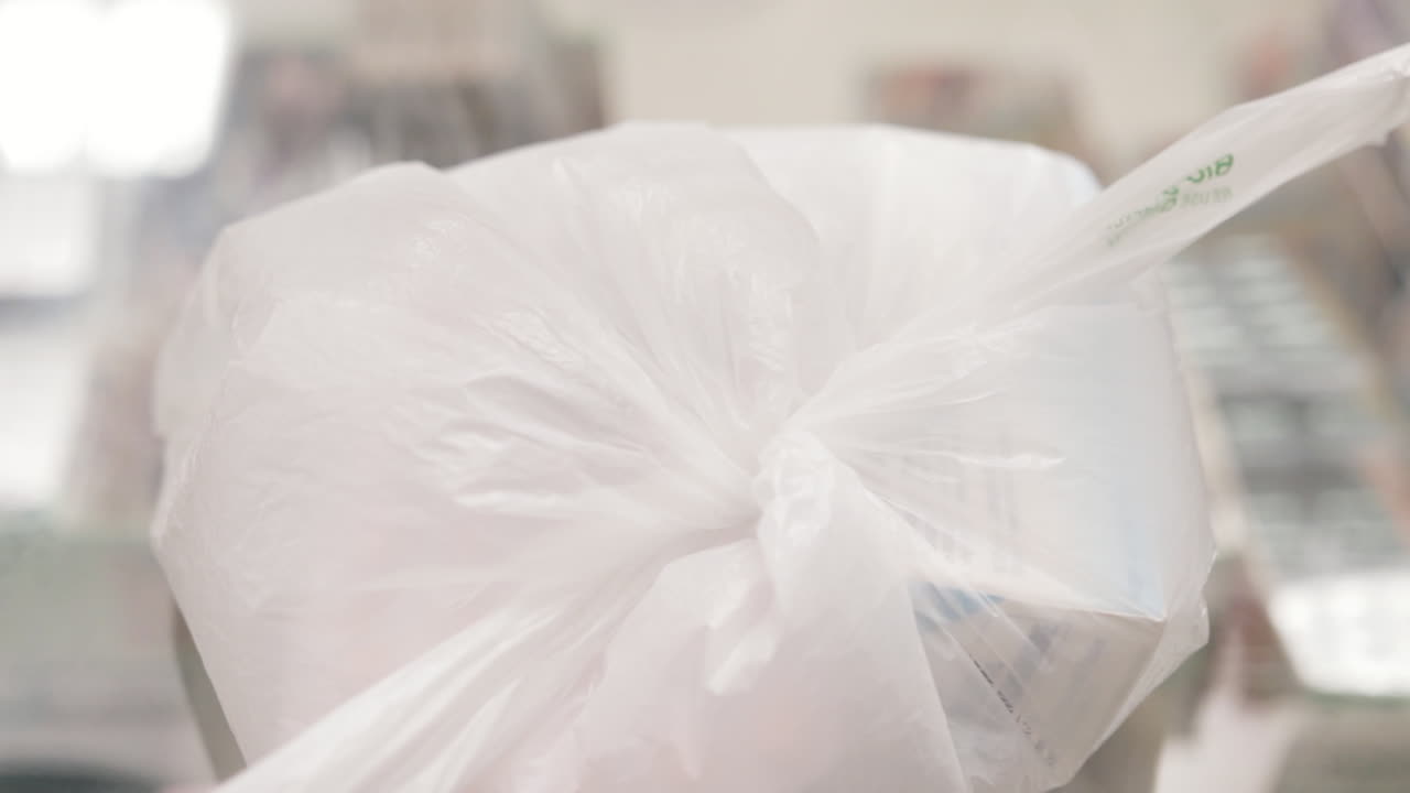 투명 유리 표면에 흰색 비닐 봉지를 묶는 손에 클로즈업 샷 확대