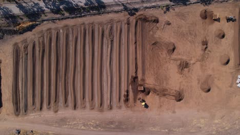 Aerial-of-yellow-tractor-scooping-up-compost-mixture-on-a-large-farm-in-mexico