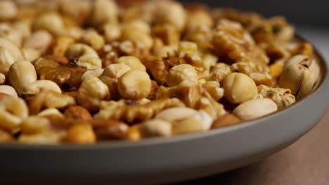 close up shot of rotating bowl containing cashews dry roasted peanuts pistachio walnuts and hazelnut nuts 1