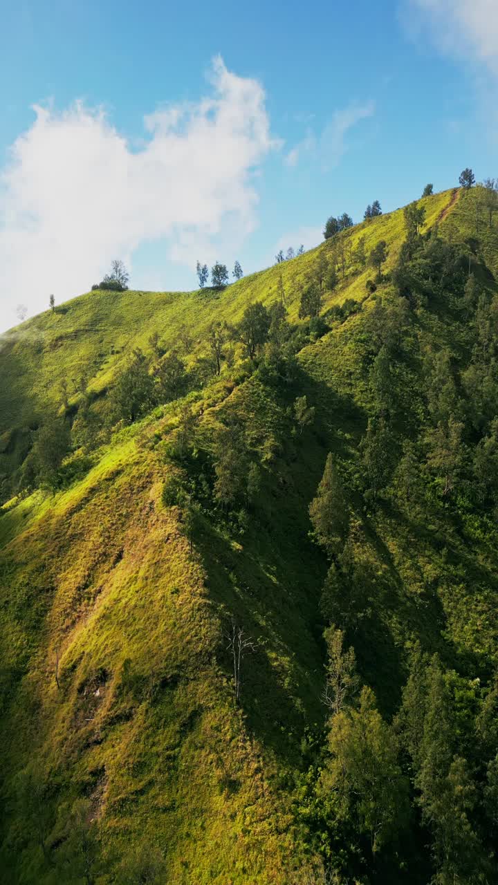 Video vertikal menangkap Bukit Trunyan di Bali bersinar di bawah matahari terbit keemasan, dengan siluet gunung dan langit pagi yang lembut menciptakan pemandangan alam yang menakjubkan.