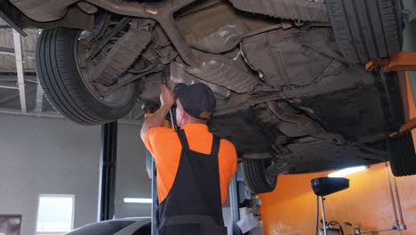 mechanic working on the undercarriage of a car lifted in a garage