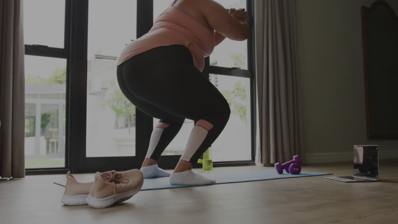 Donna che inizia un allenamento squat casalingo su un tappetino blu davanti a una porta scorrevole, generando sovrapposizioni di codice fitness