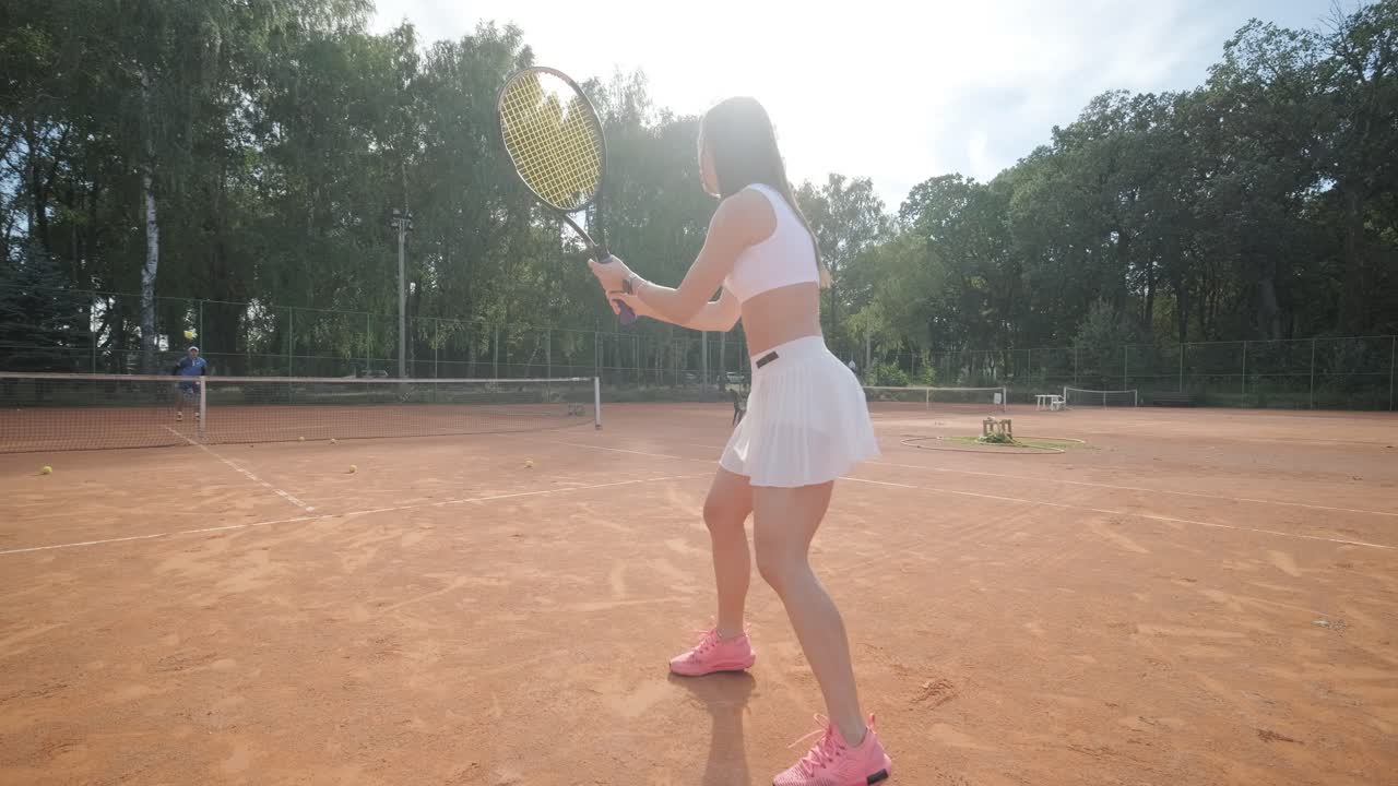 아름다운 테니스 소녀가 야외 코트에서 을 연습하고 있습니다.