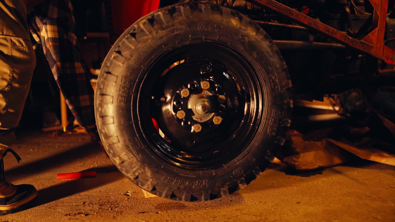 A Mounted Tractor Tire is Secured on the Axle During Vehicle Maintenance Inside a Garage Workshop - Static Shot