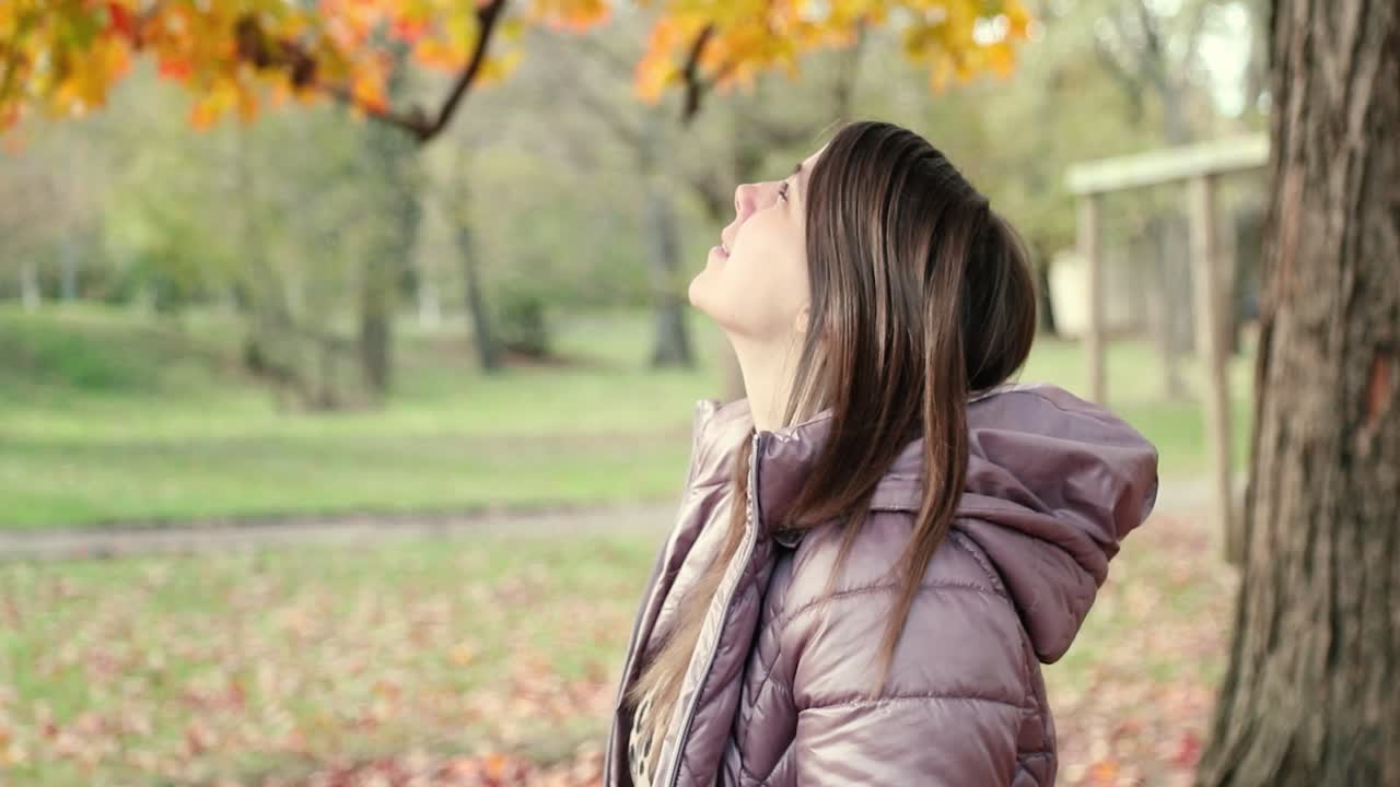 아름다운 가을 잎을 올려다보는 아름다운 소녀의 프로필 사진을 닫습니다