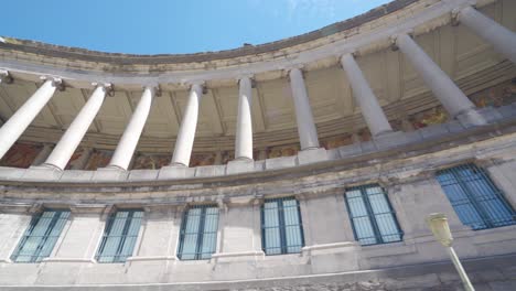 Upwards-angle-sideways-rotating-shot-of-the-columns-of-Cinquantennaire-monument-in-Brussels,-Belgium,-on-warm-sunny-summer-day-with-blue-skies