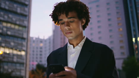 Hombre-De-Negocios-Serio-Trabajando-Con-Teléfono-Celular-En-El-Retrato-De-La-Calle-Al-Atardecer.-Chico-Enviando-Mensajes-De-Texto