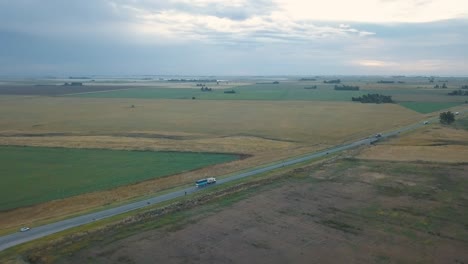 Toma-Aérea-De-Camiones-Circulando-Por-Un-Camino-Rural-En-Medio-De-Campos