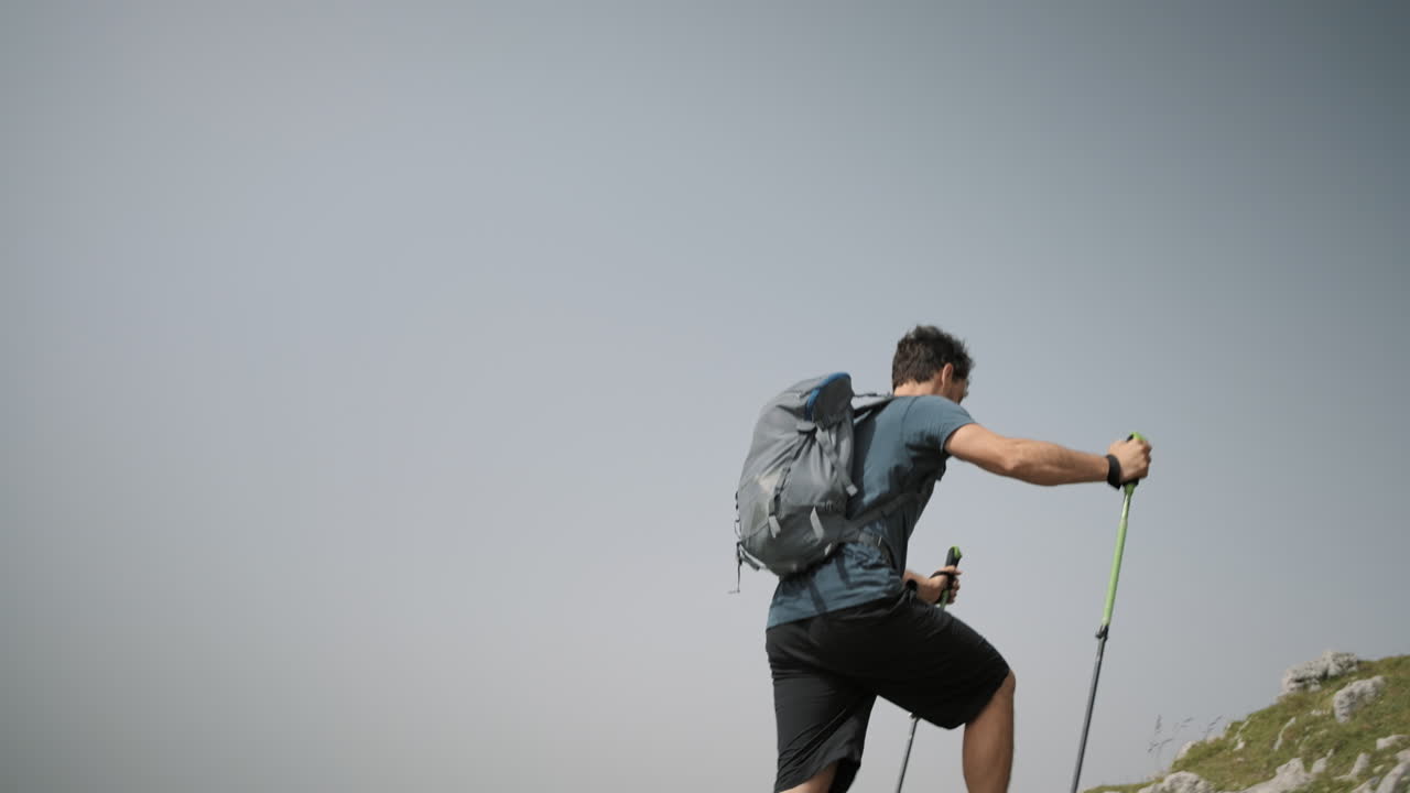excursionista subiendo una colina hacia el cartel rojo con instrucciones escritas, cielo parcialmente despejado
