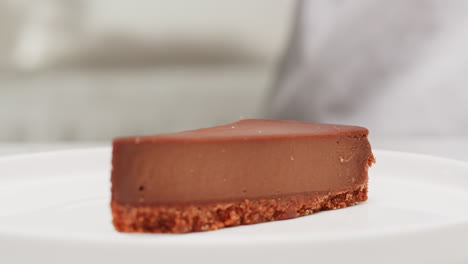 chef placing blueberry on a slice of chocolate cheesecake