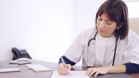 doctor filling a medical report sitting on the desk