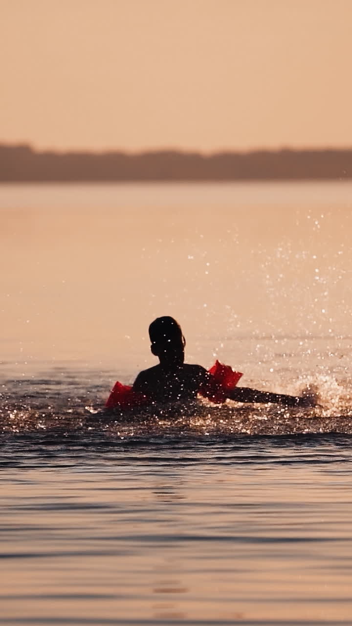 Boy playing in river water. Silhouette of boy playing splash water in river during sunset Vertical video