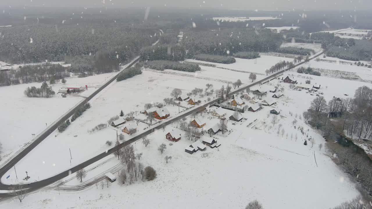 눈이 내리는 동안 작은 마을과 넓은 도로가 있는 겨울 숲, 공중 전망