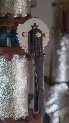 metal fittings covered with silver foil insulation and levers in boiler premise closeup. hot steam delivering pipeline system in mechanical room