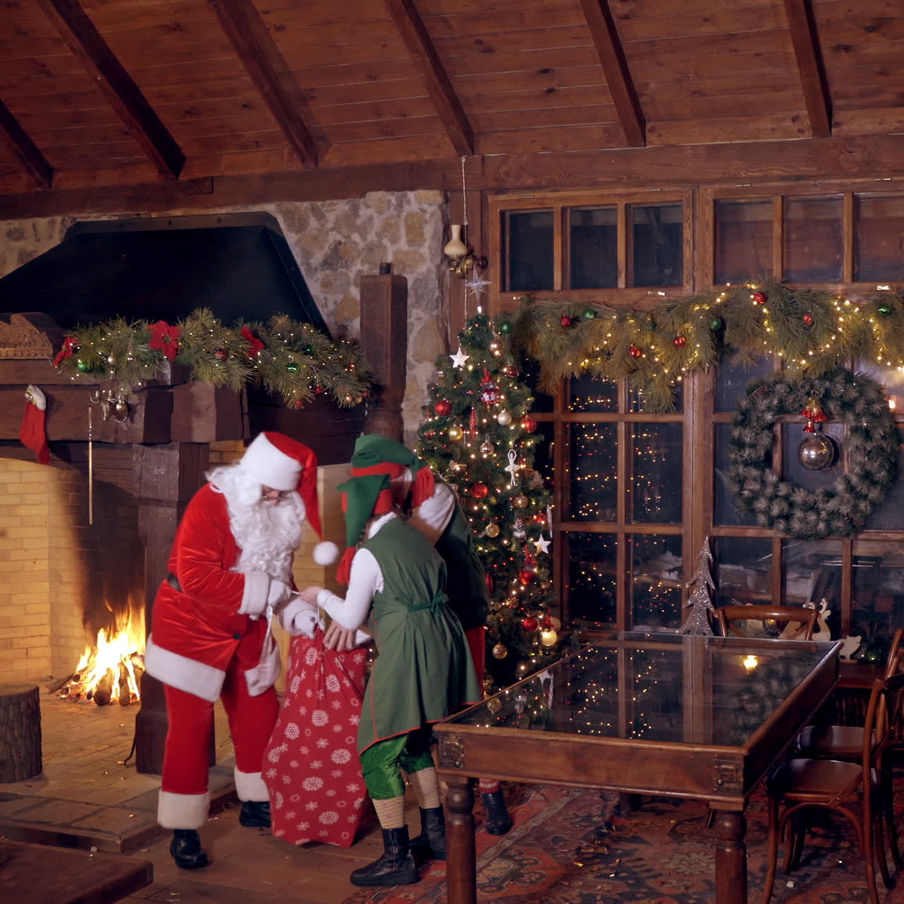 Fairy characters at Santa's residence. Santa Claus with big red bag is going to children at Christmas night. Elves saying goodbye to Santa.