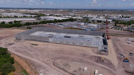 Orbiting-shot-of-a-tilt-up-building-under-construction-with-a-crane-setting-wall-panels