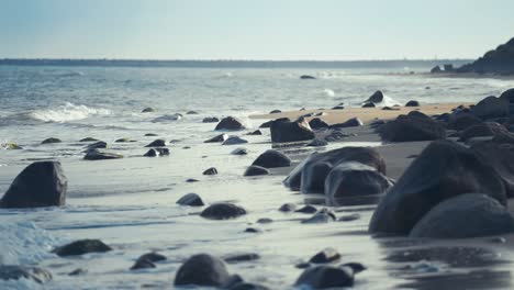 Las-Suaves-Olas-Ruedan-Lentamente-Sobre-Las-Piedras-Oscuras-De-La-Playa-De-Arena.